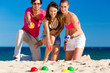 Foto: Man and women playing boule on beach Man and women playing boule on beach