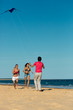 Foto: Man and women running on beach with kite Man and women running on beach with kite