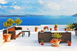 Outdoor tables and sofas on roof terrace overlooking sea in Oia