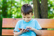 Young boy sitting on bench with tablet