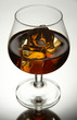 Brandy glass with ice on grey background