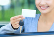 girl in a car showing a key and an empty white card