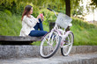Young woman sitting on the bench next to her bike and texting. U