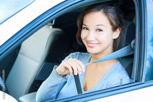 Photo: Smiling young woman in car fastens seat belt Smiling young woman in car fastens seat belt