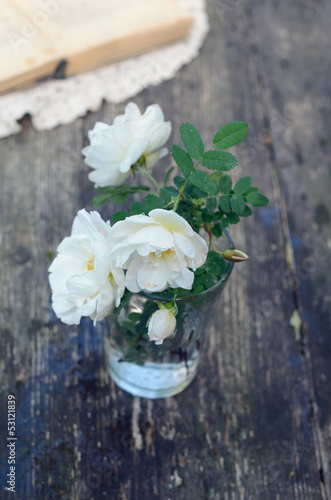 Photo: Dog rose flowers in a glass on rusted wooden table Dog rose flowers in a glass on rusted wooden table