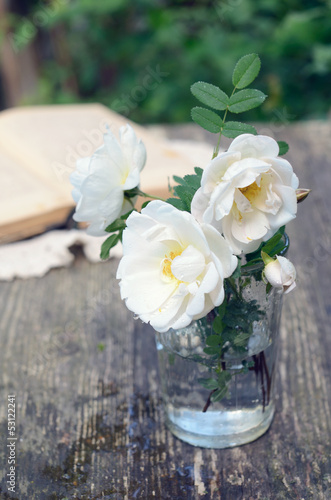 Photo: Dog rose flowers in a glass on rusted wooden table Dog rose flowers in a glass on rusted wooden table