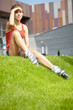 Woman skating in city. Girl going rollerblading sitting in grass