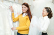 assistant  helps to girl  at shop of wedding fashion