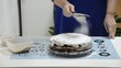 Housewife pours the powdered sugar on the cake