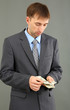 Young businessman with money on grey background.