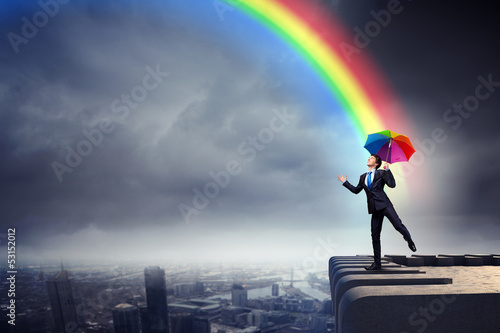 Photo: Businessman with umbrella atop of building Businessman with umbrella atop of building