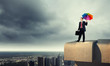 Photo: Businessman with umbrella atop of building Businessman with umbrella atop of building