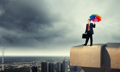 Photo: Businessman with umbrella atop of building Businessman with umbrella atop of building