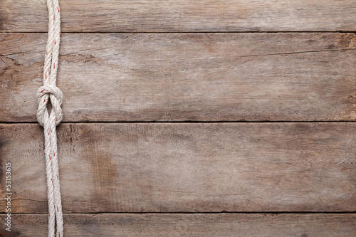Photo: Weathered wooden table background with rope reef knot, top view Weathered wooden table background with rope reef knot, top view