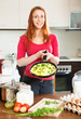 Smiling woman  with cooked omlet in pan at home kitchen
