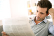Man at home reading newspaper