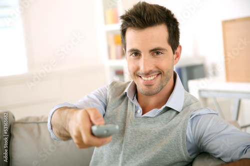 Photo: Smiling young man watching tv Smiling young man watching tv