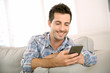 Foto: Handsome man using smartphone at home Handsome man using smartphone at home