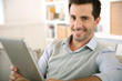 Photo: Smiling man websurfing on internet with tablet Smiling man websurfing on internet with tablet