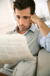 Photo: Man sitting in sofa and reading bad news Man sitting in sofa and reading bad news