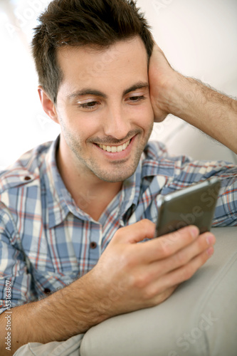 Photo: Handsome man using smartphone at home Handsome man using smartphone at home