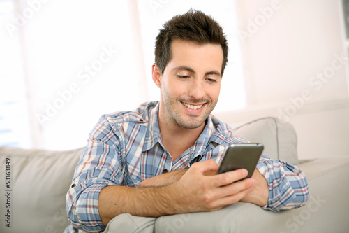 Photo: Handsome man using smartphone at home Handsome man using smartphone at home