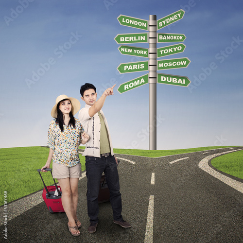 Photo: Asian couple travel with road signs outdoor Asian couple travel with road signs outdoor