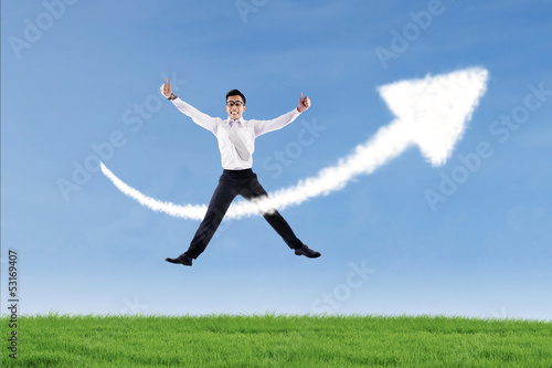 Photo: Businessman jumping and give thumbs up over success sign Businessman jumping and give thumbs up over success sign