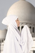 Female muslim in white praying at mosque