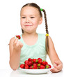 Photo: Happy little girl is eating strawberries Happy little girl is eating strawberries