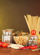 Different types of pasta, spices, tomatoes on a wooden table