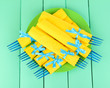 Blue plastic forks wrapped in yellow paper napkins,