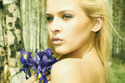 Photo: Beautiful blond woman with blue flowers in a forest Beautiful blond woman with blue flowers in a forest