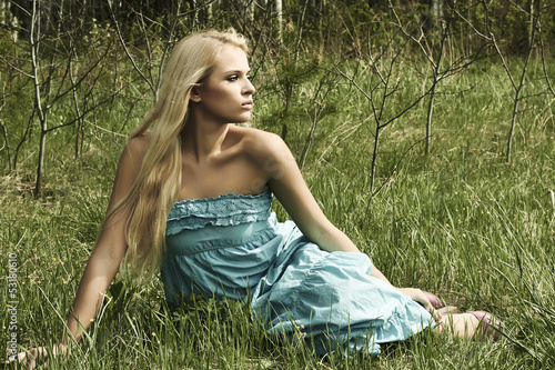 Photo: Beautiful blond woman sitting on green grass Beautiful blond woman sitting on green grass