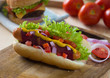 hot dog and bacon served with mustard tomatoes and plenty of bac