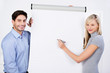 kollegen im büro stehen vor weißem flipchart