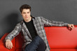 Man sitting on red sofa with hand rested on the sofa