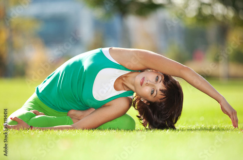 Photo: Pretty woman doing yoga exercises in the park Pretty woman doing yoga exercises in the park