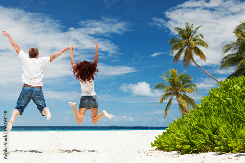 Photo: Happy couple jumping on the tropical beach Happy couple jumping on the tropical beach