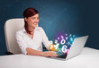 Beautiful young woman sitting at desk and typing on laptop with