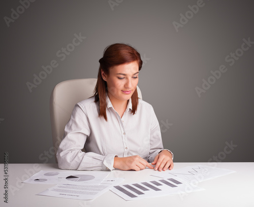 Photo: Businesswoman sitting at desk and doing paperwork Businesswoman sitting at desk and doing paperwork