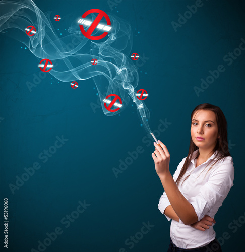 Photo: Young woman smoking dangerous cigarette with no smoking signs Young woman smoking dangerous cigarette with no smoking signs