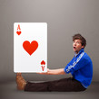 Young man holding a red heart ace