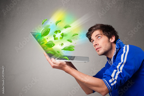 Photo: Casual boy holding laptop with recycle and environmental symbols Casual boy holding laptop with recycle and environmental symbols