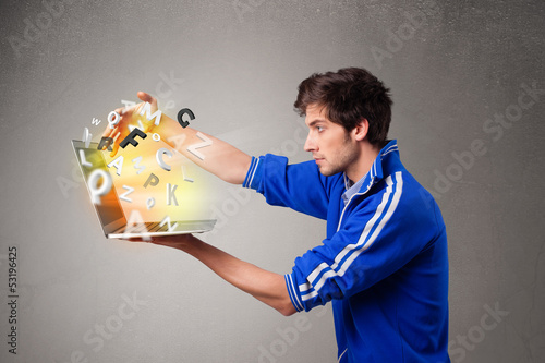 Photo: Attractive young man hoding notebook with colorful letters Attractive young man hoding notebook with colorful letters