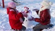 Happy girls playing a game in front of a snowman