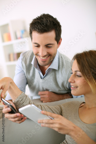 Photo: Young couple using smartphone at home Young couple using smartphone at home