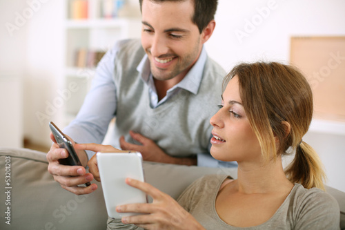 Photo: Young couple using smartphone at home Young couple using smartphone at home