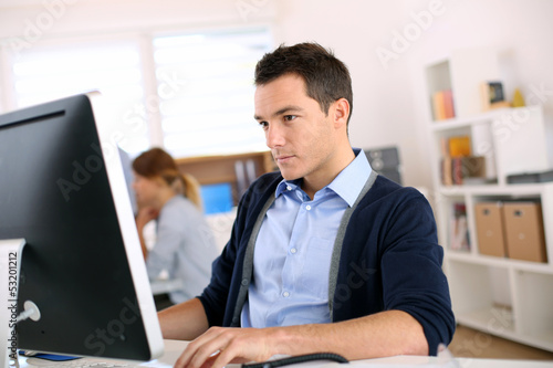 Photo: Man working in office in front of desktop computer Man working in office in front of desktop computer