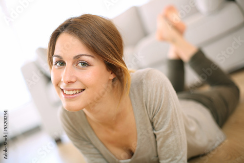 Photo: Smiling girl relaxing on the floor at home Smiling girl relaxing on the floor at home
